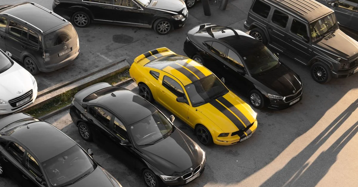 Vue du dessus de diverses voitures garées dans un parking, avec une voiture de sport jaune.
