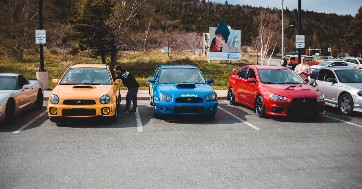 Des voitures colorées exposées en plein air dans un parking urbain par une journée ensoleillée.