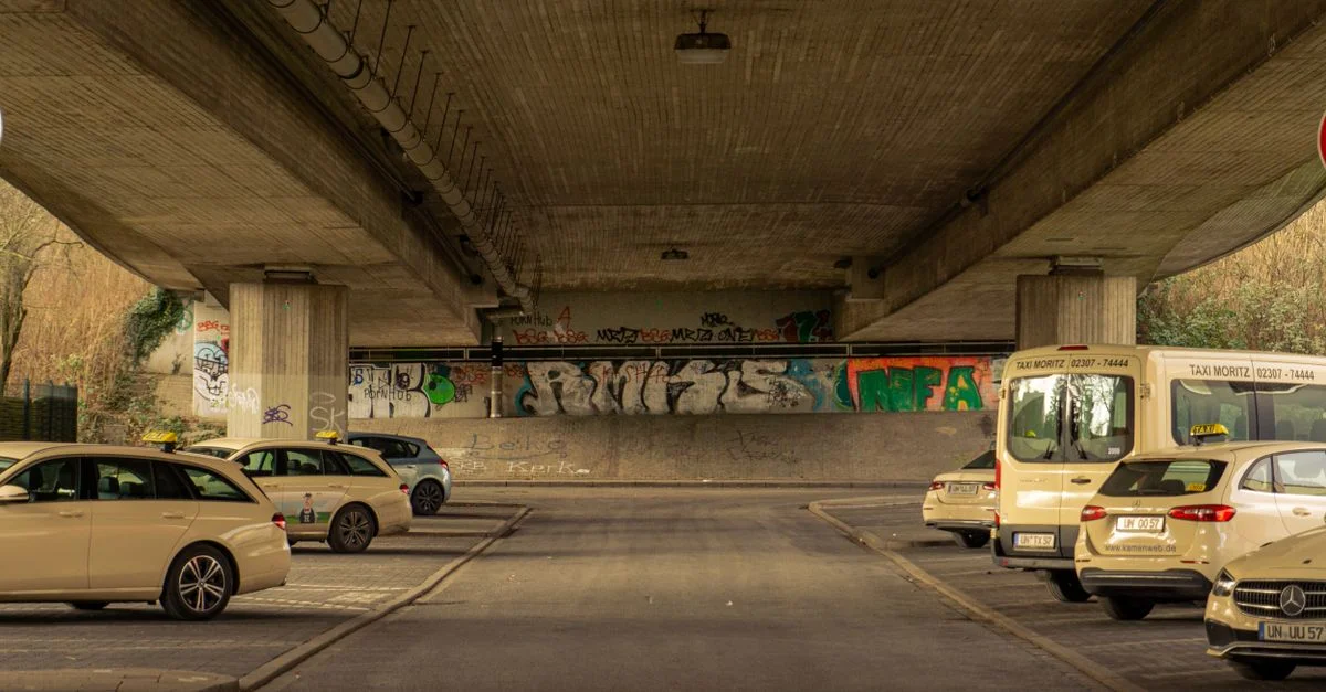 Passage souterrain en béton à Kamen, en Allemagne, avec des voitures garées et des graffitis vibrants.