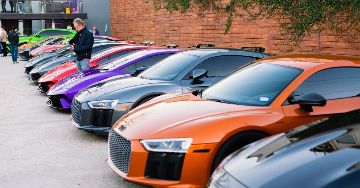 Une rangée de voitures de sport de luxe garées à l'extérieur lors d'un événement de présentation automobile vibrant.